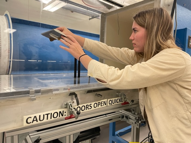 Student working with materials in a wind tunnel