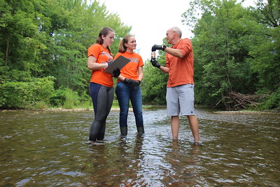 Professor Charles Driscoll in a river with two student researchers