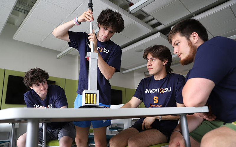 Four students working on a cane that would help people rise from a seated position
