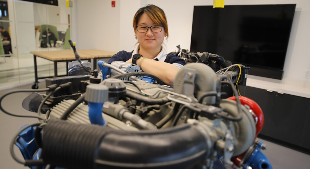 Professor Andrea Shen with an automobile engine