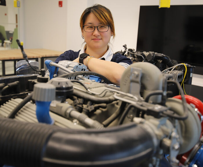 Professor Andrea Shen with an automobile engine