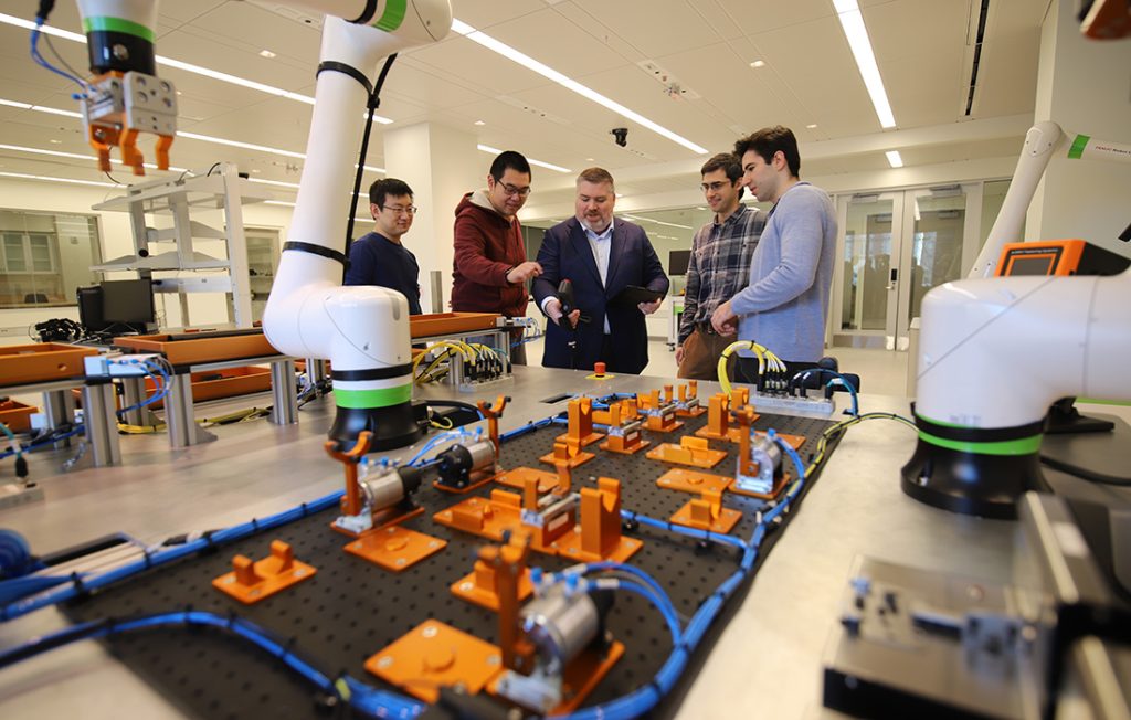 Center for Advanced Semiconductor faculty looking over robotic manufacturing equipment