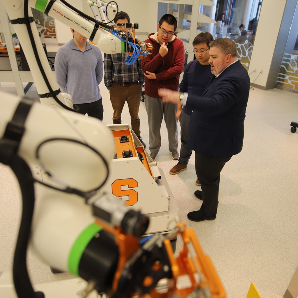 Center for Advanced Semiconductor faculty looking over robotic manufacturing equipment
