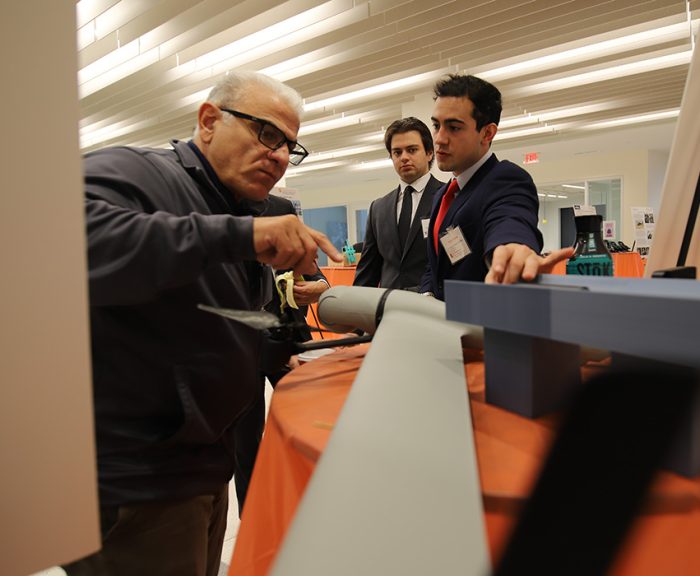 Engineering students demonstrating their senior design project to an industry evaluator