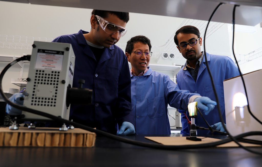 Professor Quinn Qiao and two graduate students working on battery research in an advanced lab facility
