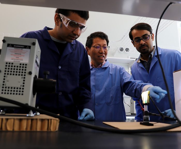 Professor Quinn Qiao and two graduate students working on battery research in an advanced lab facility