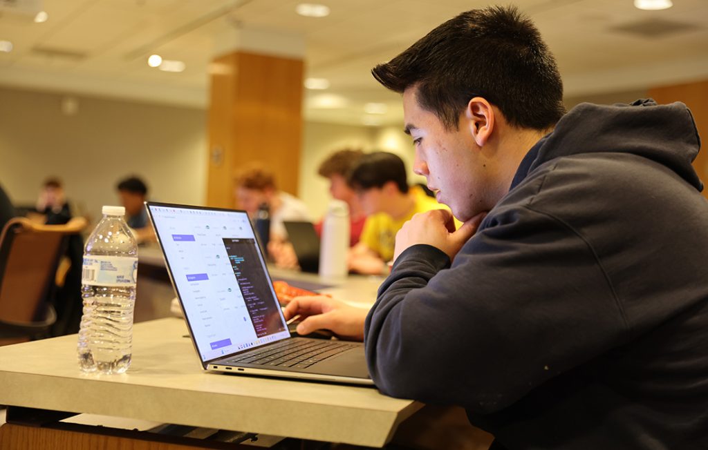 Students working on laptops during a cybersecurity competition 