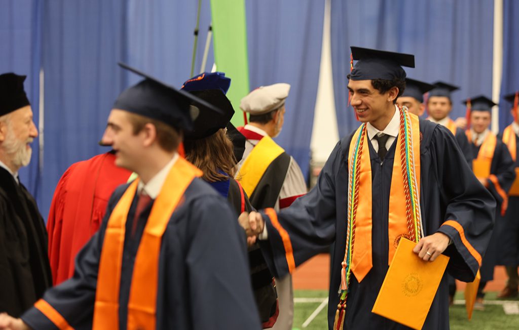 A student shaking hands with faculty at Convocation