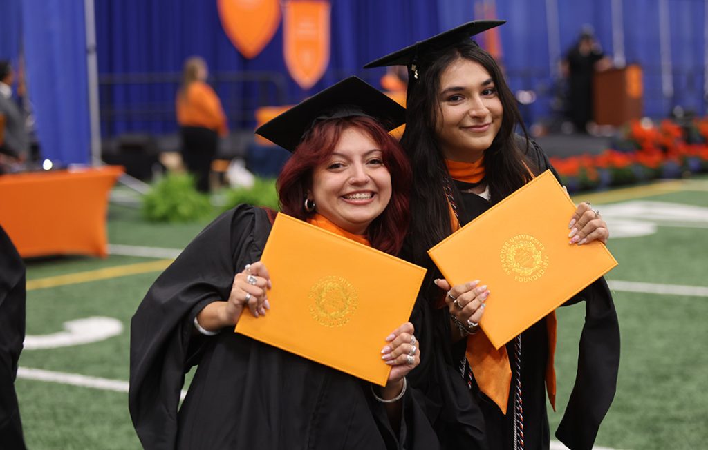 Two students with their diploma holders