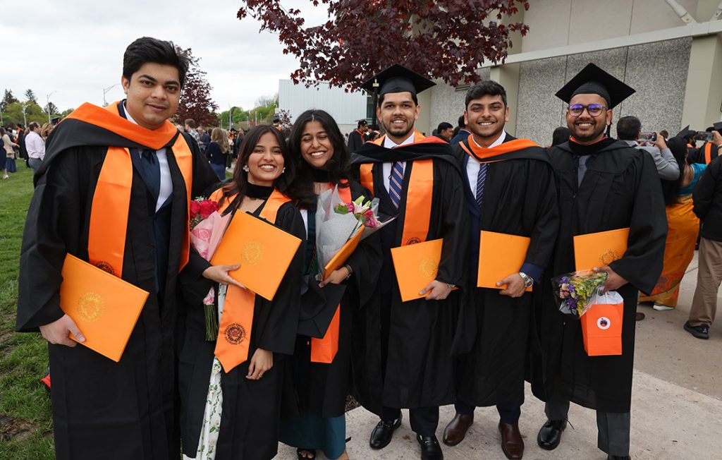 A group of students celebrating with their friends outside of the Engineering and Computer Science Convocation