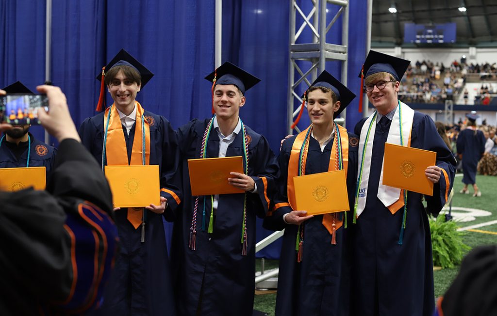 Four students celebrating after walking off the stage at the 2026 Engineering and Computer Science Convocation