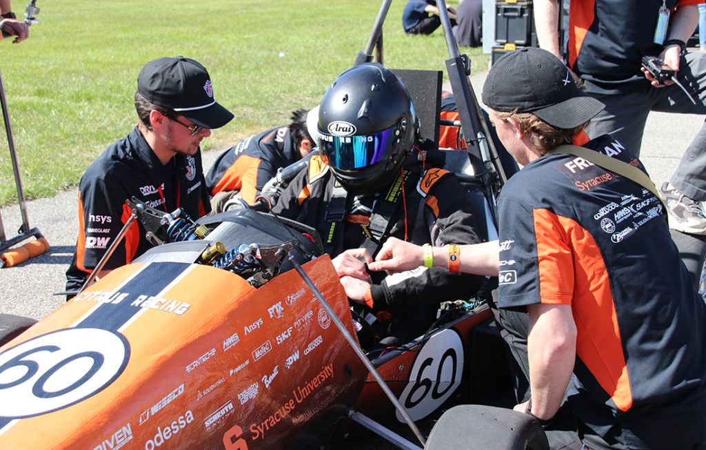 Citrus Racing team members preparing the car and driver for a competition at the Formula SAE event in Michigan