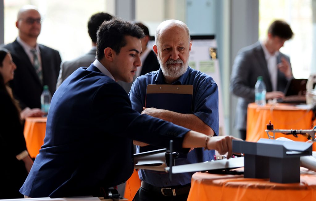 A student demonstrating a mechanical and aerospace engineering prototype to Professor Ian Shapiro