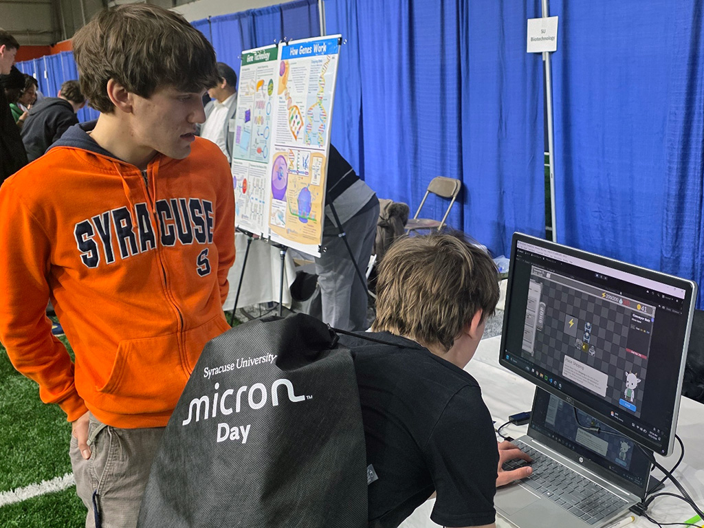 A man showing a boy how to play a game on the computer.